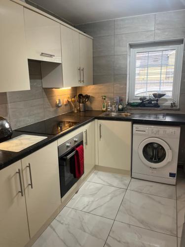 a kitchen with white cabinets and a washing machine at Castell Cottages Central with Parking in Caerphilly