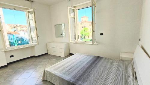 a white room with a bed and two windows at casa Camillo in Novara