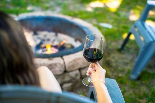 a woman holding a glass of wine in front of a fire pit at The Cliff House Hot Tub Kayaks & Game Room in Dresden