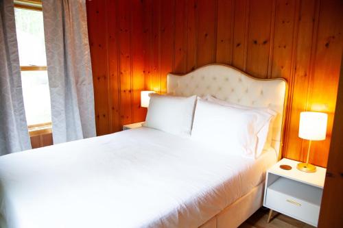 a bedroom with a white bed with a wooden wall at The Cliff House Hot Tub Kayaks & Game Room in Dresden