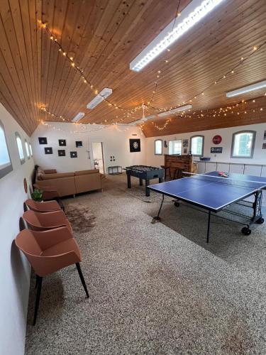 a large room with a ping pong table and chairs at The house in the countryside close to MCH in Herning