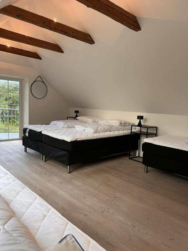 two beds in a large room with wooden floors at The house in the countryside close to MCH in Herning