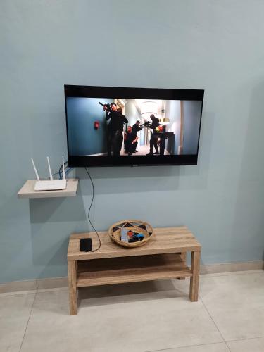 a living room with a table and a tv on a wall at Dreamers nest in Richards Bay