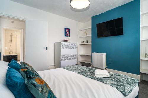 a bedroom with a white bed with a blue wall at Sage House (Town-Centre Flat) in Allington