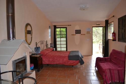 a bedroom with a red bed and a fireplace at La Casa de la Montaña in Cortes de Arenoso