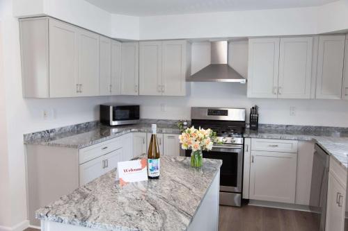 a kitchen with white cabinets and a bottle of wine on a counter at Heron Hideaway Game Room within walking distance to HWS & Seneca Lake in Geneva