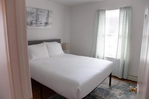 a white bed in a room with a window at Heron Hideaway Game Room within walking distance to HWS & Seneca Lake in Geneva