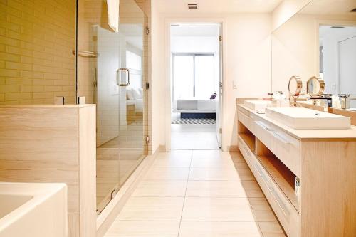 Un baño blanco con dos lavabos y una ducha. en Luxury apartment with endless ocean views -Daily resort fee and parking not included-, en Hollywood