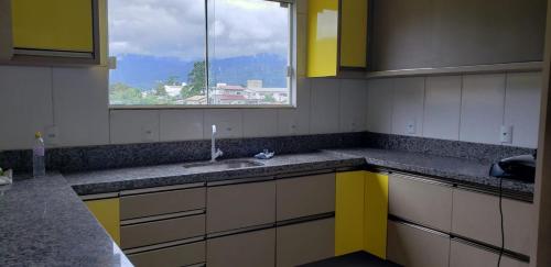 a kitchen with yellow and white cabinets and a window at Casa da Sorte - campo, montanha, natureza e caminho da praia in Santo Amaro da Imperatriz