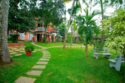 un parc avec des bancs et des palmiers et un bâtiment dans l'établissement Doctors Ayurveda Heritage, à Varkala