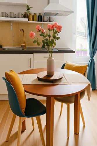 a dining room table with a vase of flowers on it at Le King & Suites étoilées in Gréoux-les-Bains