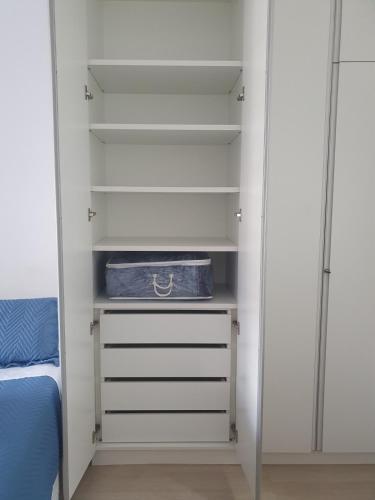 a closet with white shelves and a bed at Flat Novo2 - Café, Ar, Estac e Internet in Barueri