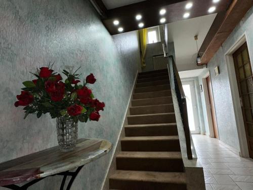 a vase of red roses sitting on a table next to a staircase at Les Vignes - Villa à 1 mn de Metz in Plappeville