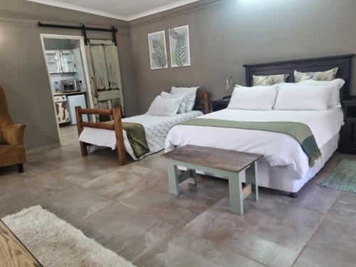 a bedroom with two beds and a chair and a table at La Mouna 4 in Bultfontein in Bultfontein