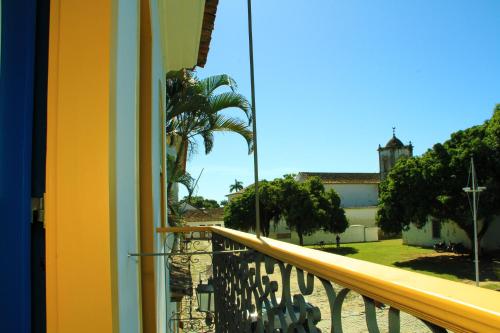 a balcony with a view of a palm tree and a building at Pousada do Cais in Paraty