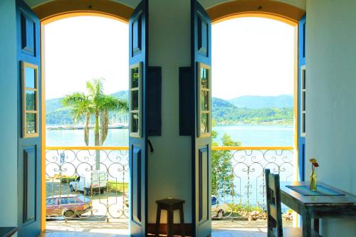 an open door to a balcony with a view of the water at Pousada do Cais in Paraty