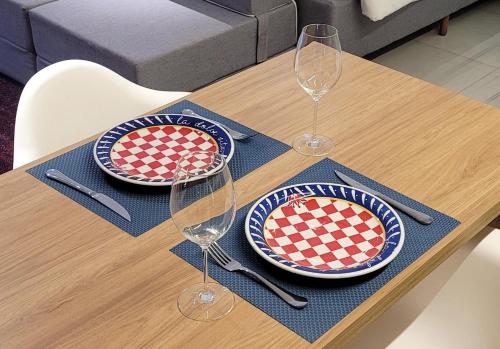a table with two plates and wine glasses on it at Blend Coliving One - 2b in Ribeirão Preto