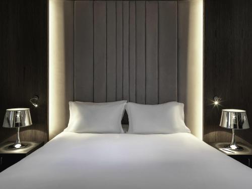 a large white bed with two lamps on both sides at Sofitel Athens Airport in Athens
