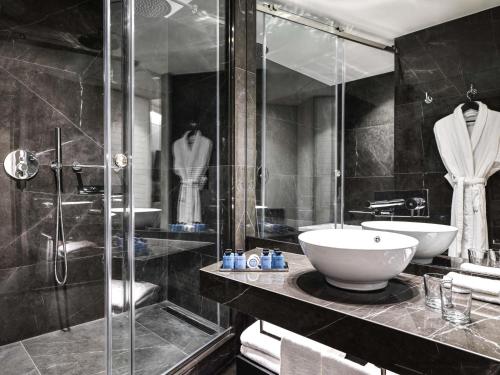 a bathroom with a sink and a glass shower at Sofitel Athens Airport in Athens