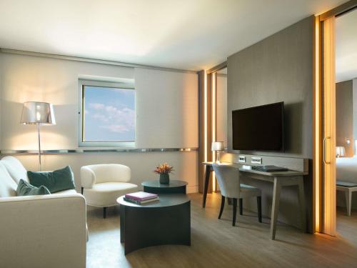 a living room with a couch and a desk with a television at Sofitel Athens Airport in Athens