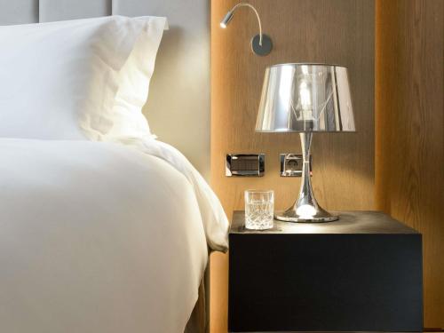 a lamp on a night stand next to a bed at Sofitel Athens Airport in Athens