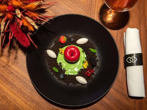 a black plate with a dessert in the shape of a face at Sofitel Athens Airport in Athens