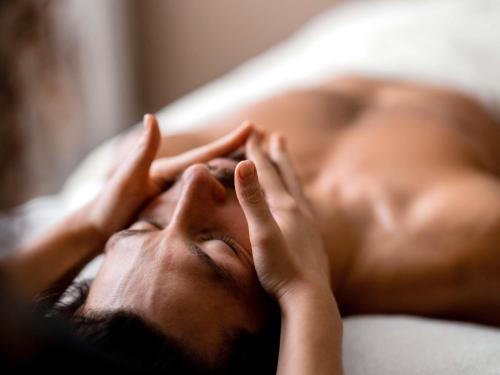 a man laying on a bed with his hands on his face at Sofitel Athens Airport in Athens