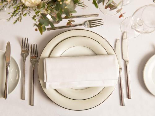 a white table with silverware and a plate with a napkin at Sofitel Athens Airport in Athens