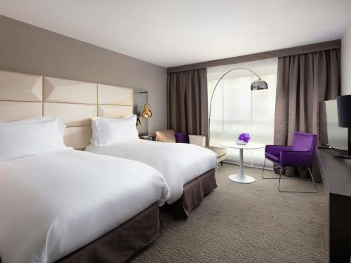 a hotel room with two beds and a table at Sofitel Warsaw Victoria in Warsaw