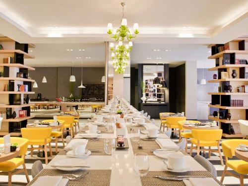 a long dining room with white tables and yellow chairs at Sofitel Warsaw Victoria in Warsaw