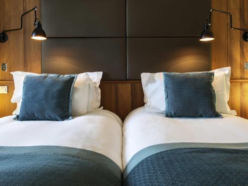 two beds with blue pillows in a room at Sofitel Grand Sopot in Sopot