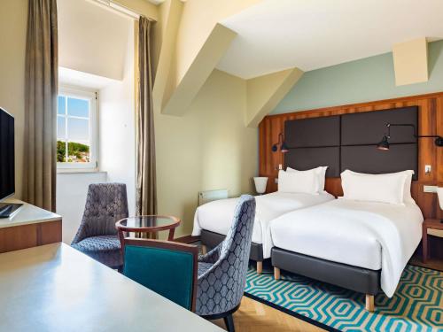 a hotel room with two beds and a table and chairs at Sofitel Grand Sopot in Sopot