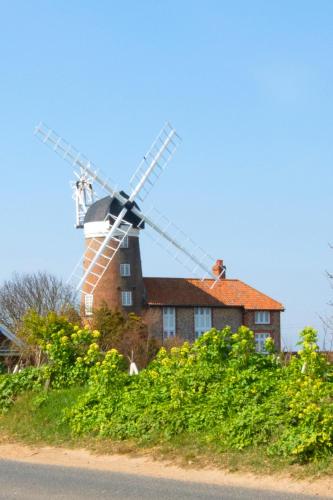 a house with a windmill on top of it at Whistles in Weybourne
