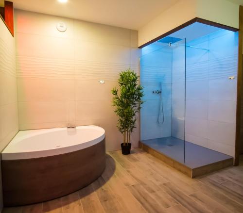 a bathroom with a tub and a glass shower at La Suite Interdite Jacuzzi, Sauna & Pièce Secrète in Nancy