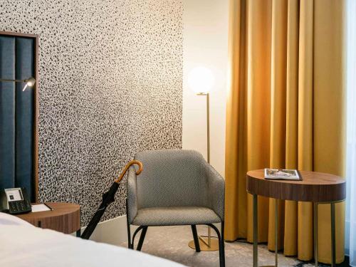 a room with a chair and a desk and a bed at Century Old Town Prague - MGallery Collection in Prague