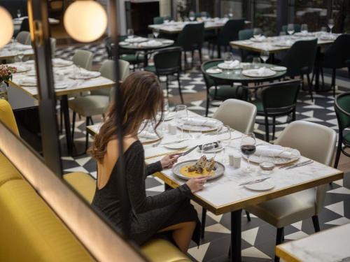 a woman sitting at a table in a restaurant at Century Old Town Prague - MGallery Collection in Prague