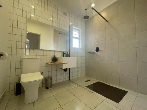 a bathroom with a toilet and a shower with a mirror at Aviator's Nest in Kempton Park