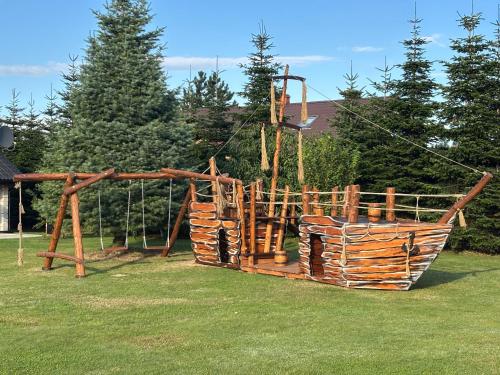 a wooden playground in a park with a swing at Domki Kaktus in Osieki
