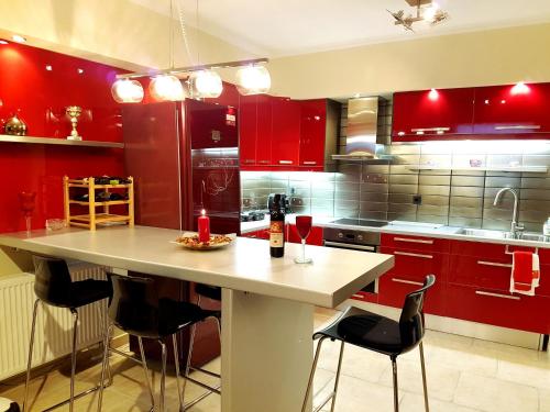 Áyios VasíliosにあるVilla Vanessaのキッチン(赤いキャビネット、ワイン1本付きのテーブル付)