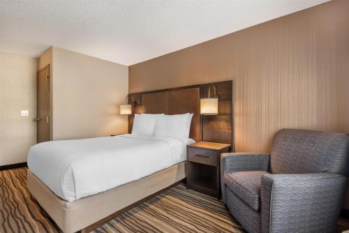a hotel room with a bed and a chair at Best Western PLUS Calgary Centre Inn in Calgary