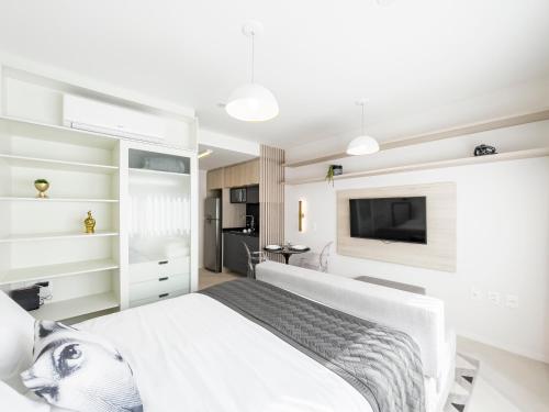 a bedroom with a white bed and a flat screen tv at Charlie Porto Alegre Moinhos in Porto Alegre