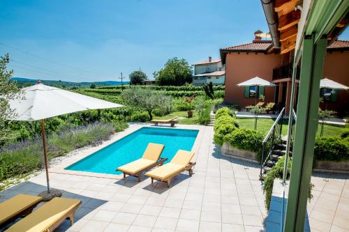 a swimming pool with two chairs and an umbrella at Zoi Apartments in Dobrovo