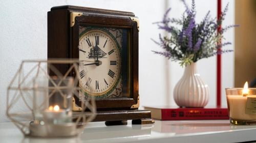 a clock on a table with a vase of flowers and candles at La Clessidra - Rome Ciampino Airport in Ciampino