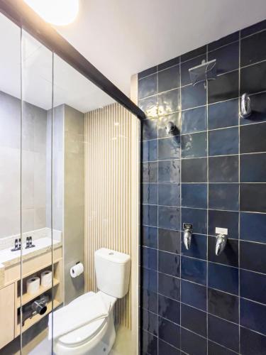 a bathroom with a toilet and a shower with blue tiles at Charlie Porto Alegre Moinhos in Porto Alegre