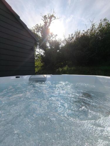 a swimming pool with the sun in the background at The Pumphouse with Hot Tub in Weymouth