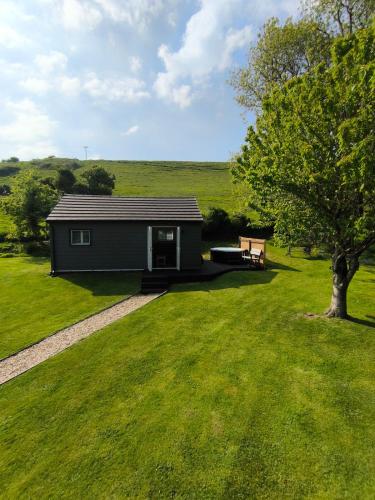 a small shed with a bench in a field at The Pumphouse with Hot Tub in Weymouth