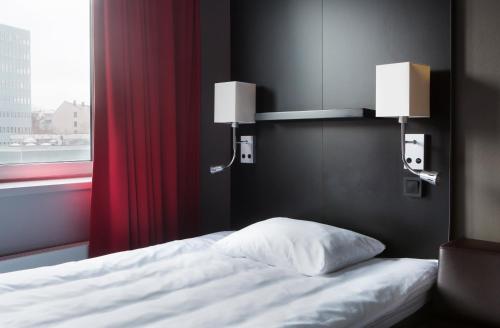 a bedroom with a bed with a red curtain and two lights at Comfort Hotel Xpress Youngstorget in Oslo