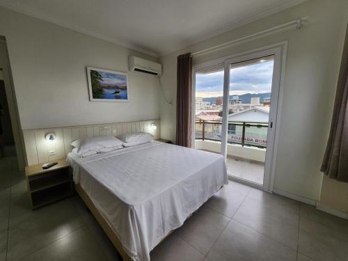 Un dormitorio con una cama y una ventana grande. en Bomar Residence, en Bombinhas