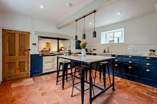 a kitchen with blue cabinets and a table with stools at Red House in Methwold