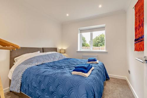 a bedroom with a bed with blue sheets and a window at Pheasant House - Cawston in Cawston